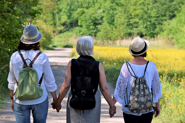 Tri staršie ženy sa držia za ruky a kráčajú po chodníku v prírode.jpg