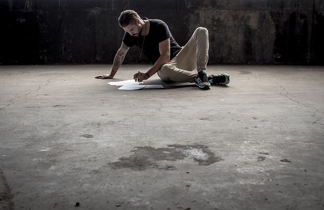 Muž sedí na podlahe a kreslí na papier